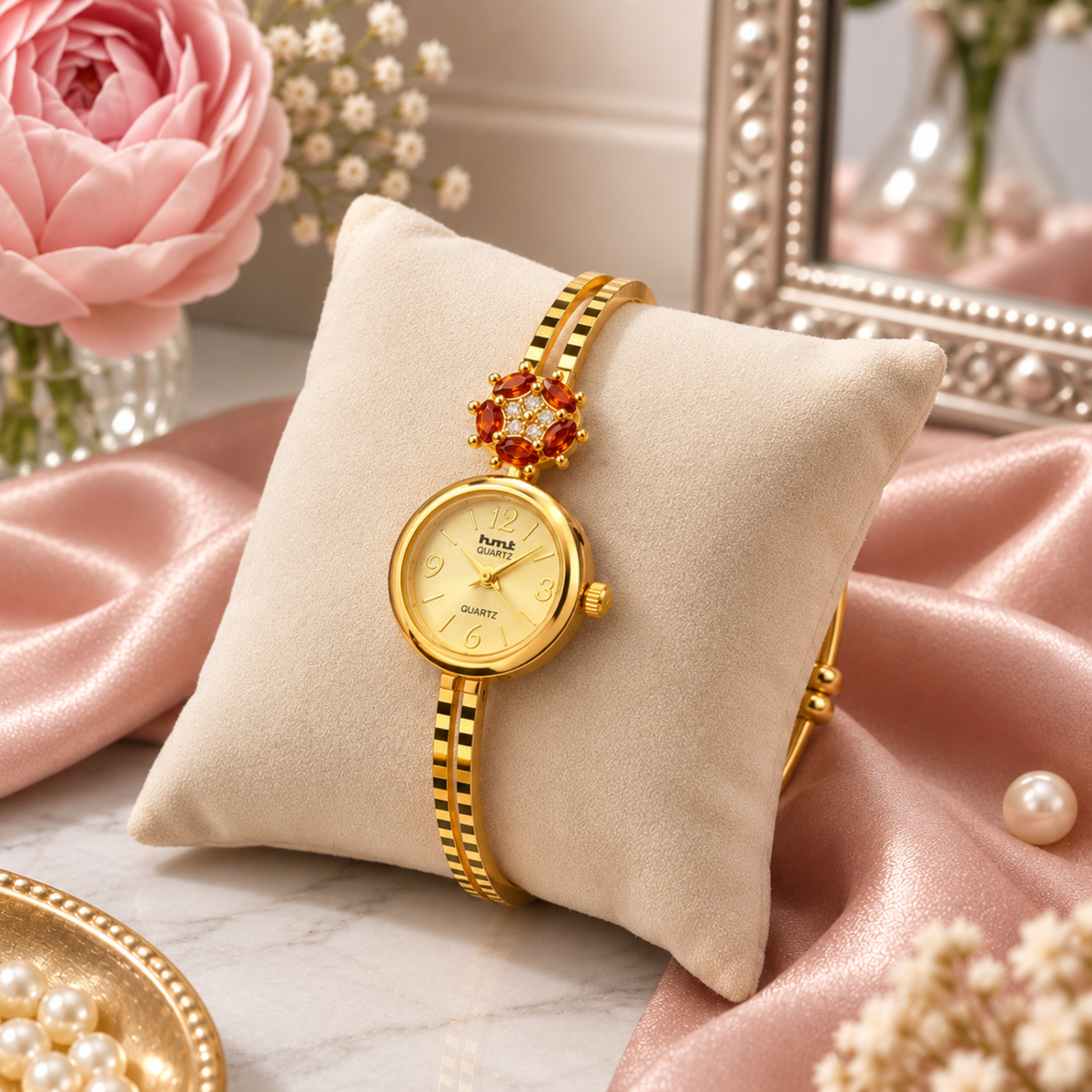 Close up of gold garnet flower bangle watch on display cushion