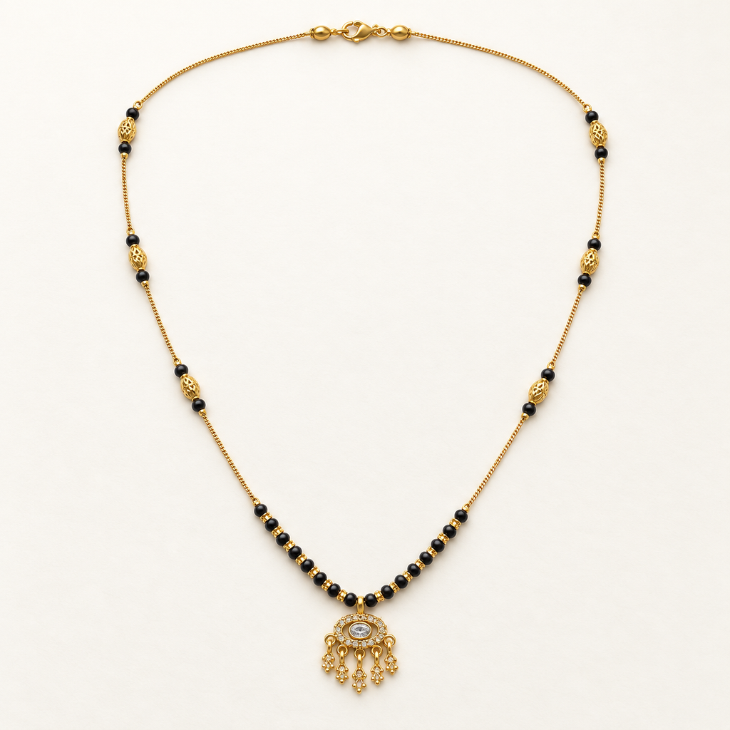 A gold chain necklace with small black beads, decorative gold spacer beads, and a dangling ornate gold pendant featuring a central clear stone, displayed on a clean white background.