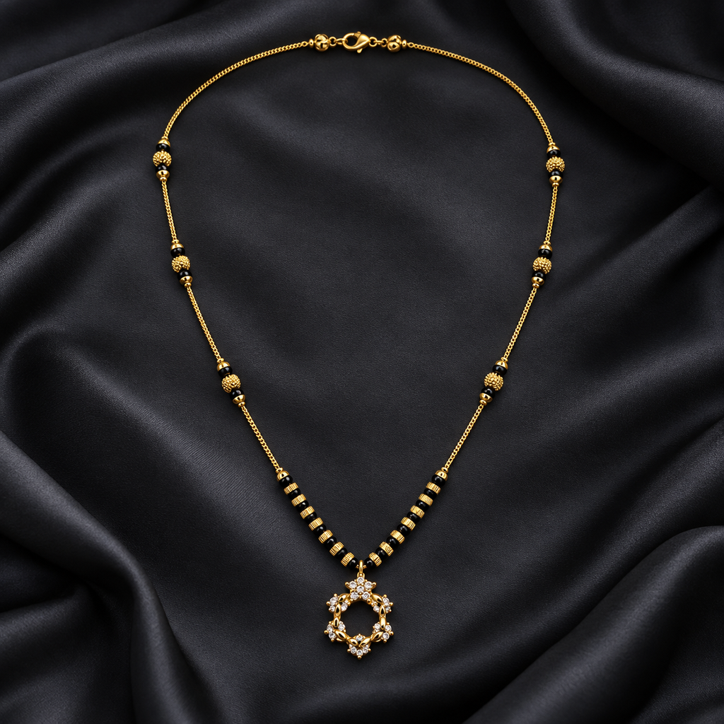 A gold-toned beaded necklace with a circular pendant set with clear stones, displayed on draped black satin fabric.