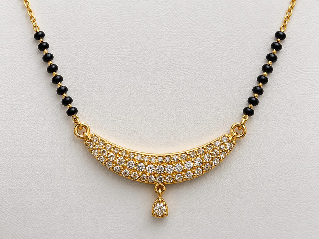 Gold necklace with a curved pavé pendant set with clear stones, flanked by black bead sections on a white textured background.