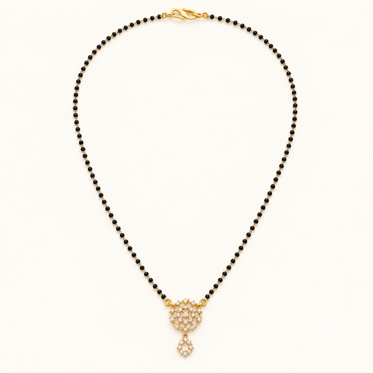 Gold-tone black bead mangalsutra with a sparkling floral cluster pendant and small dangling charm on a white background.