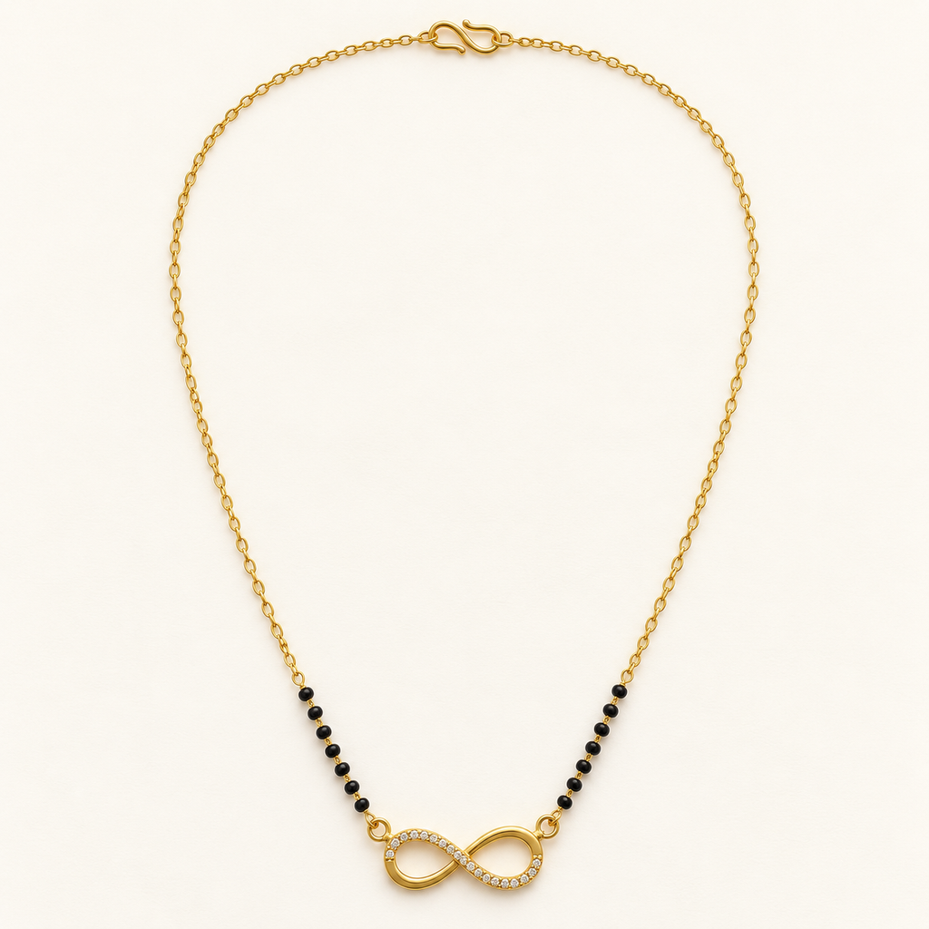 A gold chain necklace featuring a central infinity symbol paved with small clear stones, flanked by strands of small black beads, on a light cream background.